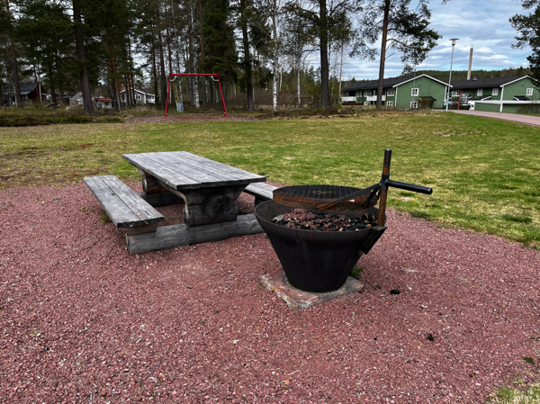 Bänkbord och eldstad med gungställningen i bakgrunden