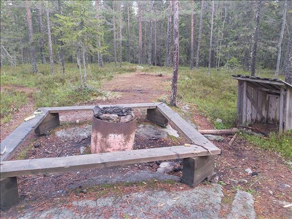 Eldstad med bänkar runt och vedförråd