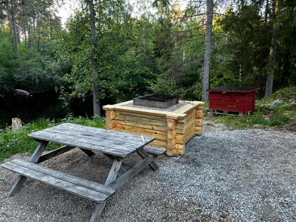 Bänkbord, eldstad med galler och vedförrådet bakom