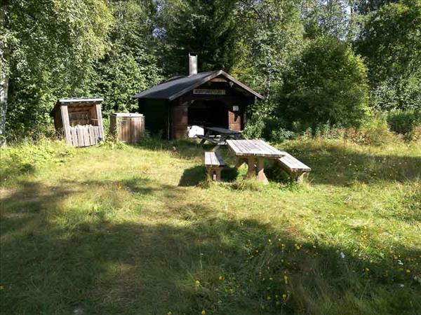 Picknickbord som står utanför grillstugan i bakgrunden