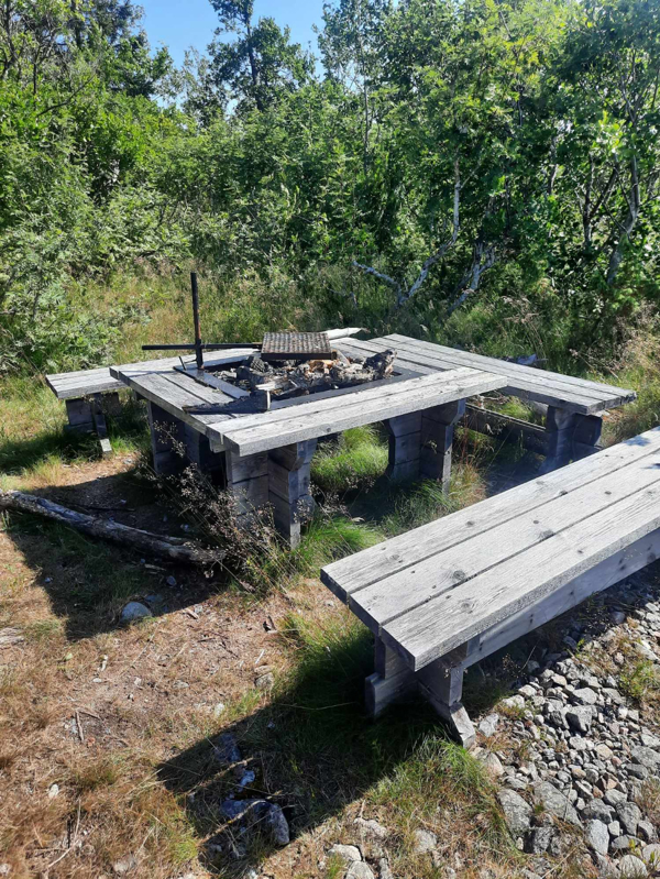 Uppbyggd grillplats med fast galler och tre sittbänkar