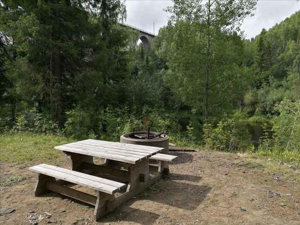 Eldstad med picknickbord intill. Den andra bron i bakgrunden