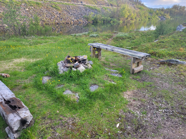 Eldstad och bänkar med E10 i bakgrund