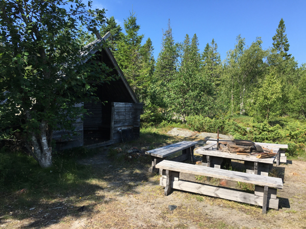 Vindskydd med sittplatser och eldstad med bänkar och grillgaller 