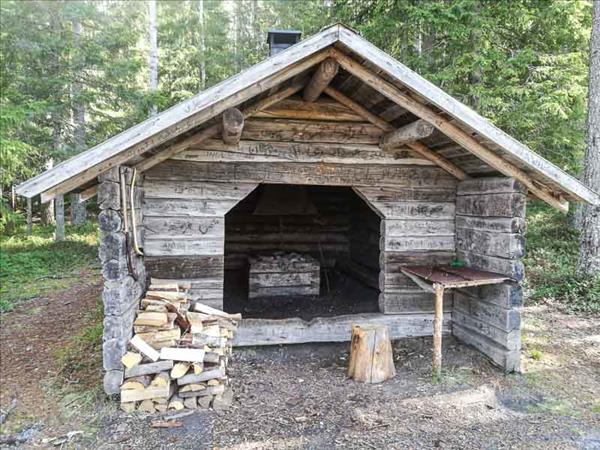 En timrad grillstuga med eldstad inuti och skorsten